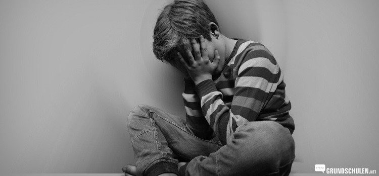 Burnout bei Kindern - Junge sitzt traurig am Boden